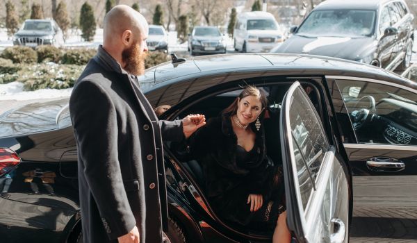 un chofer ayudando a salir del coche a una mujer en un servicio de enoturismo en Madrid